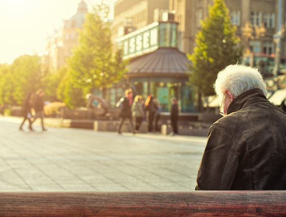 An elderly gentleman sitting on a bench.
